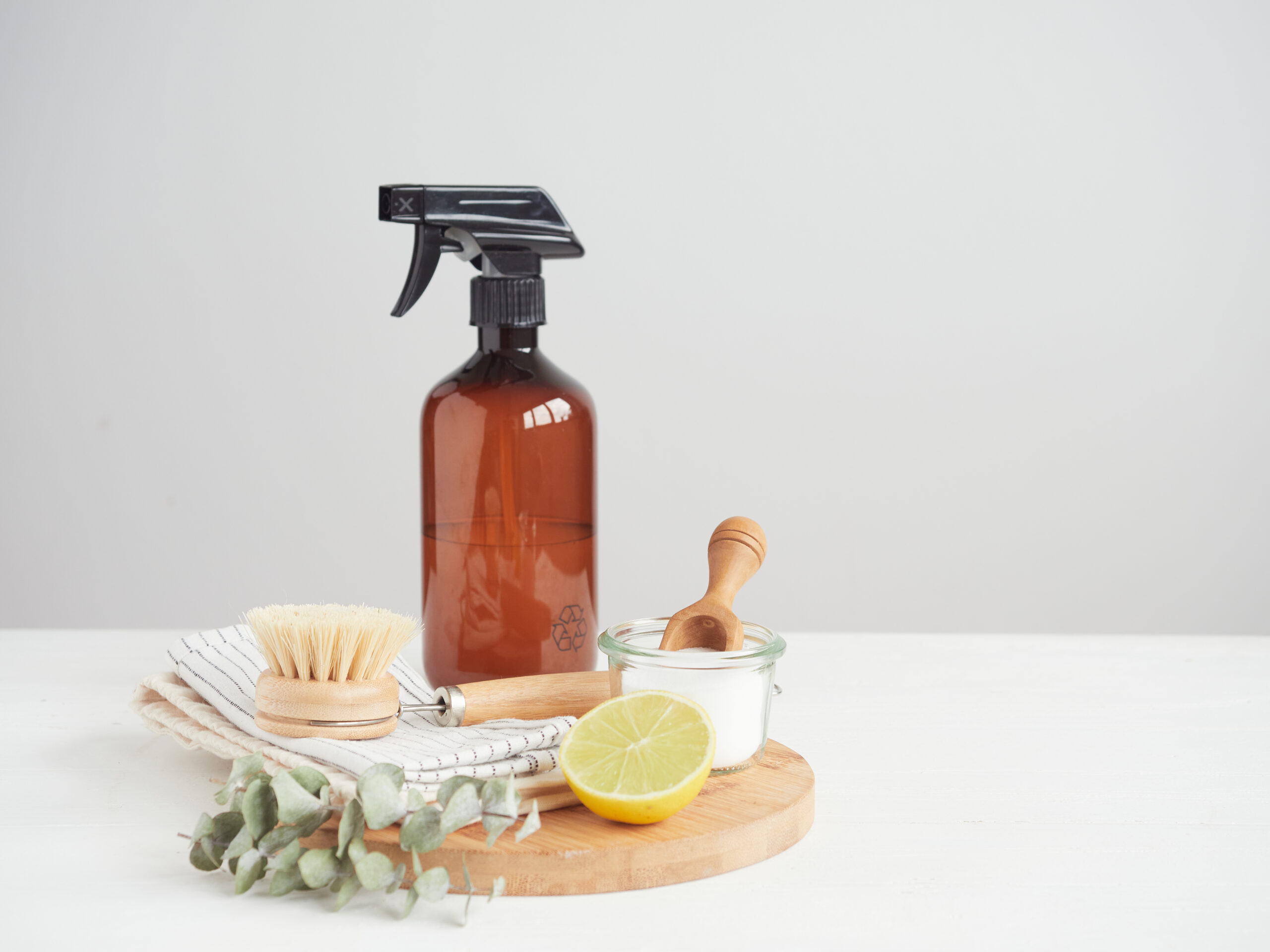 Natural cleaning product in reusable recycled glass bottle. Lemon and baking soda. Natural bristle brush and cotton cloths. Zero waste concept. Plastic free.