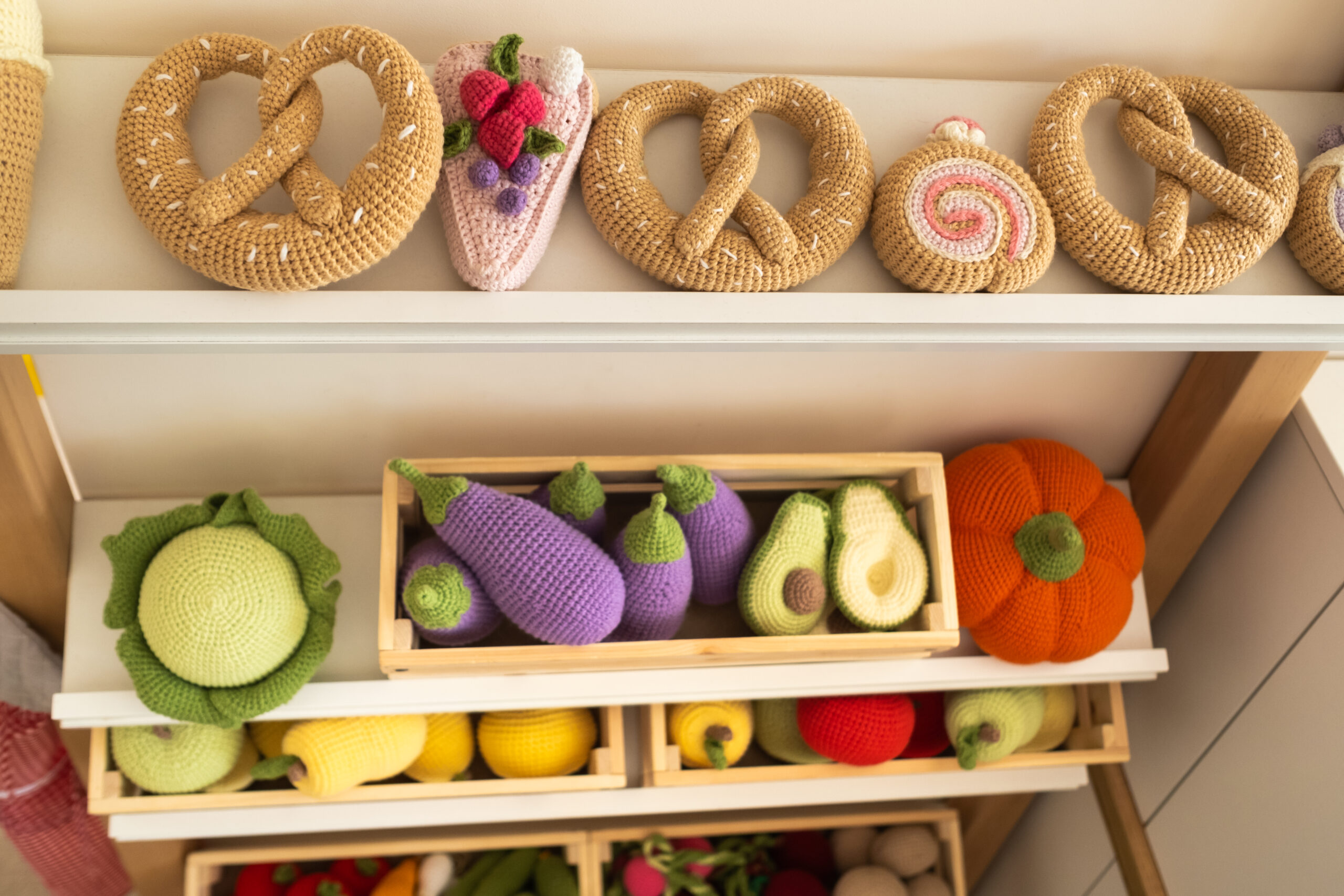 Artificial food in the children's kitchen. On the shelf are vegetables and fruits made of knitted threads